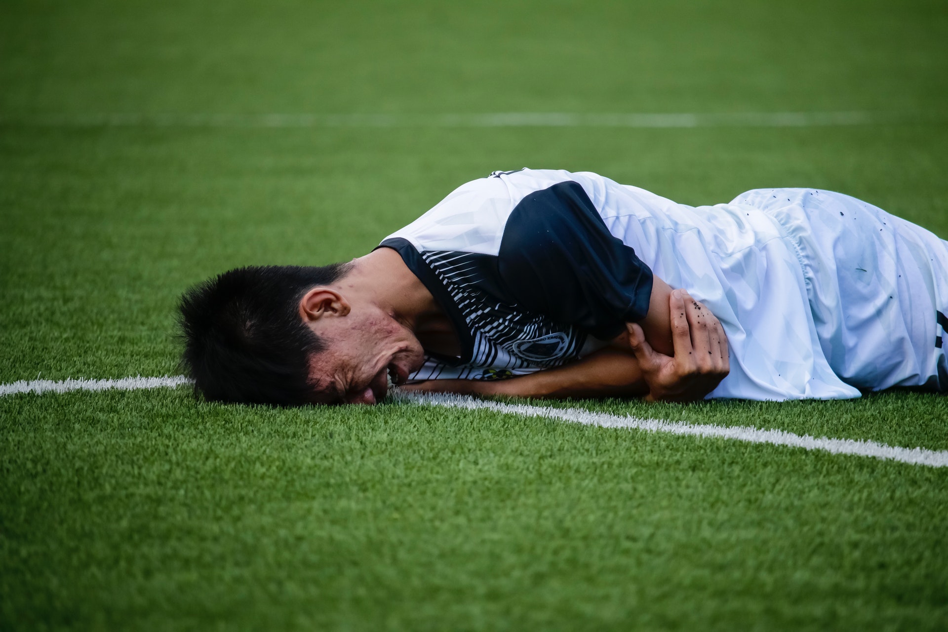Crying man laying down on soccer pitch