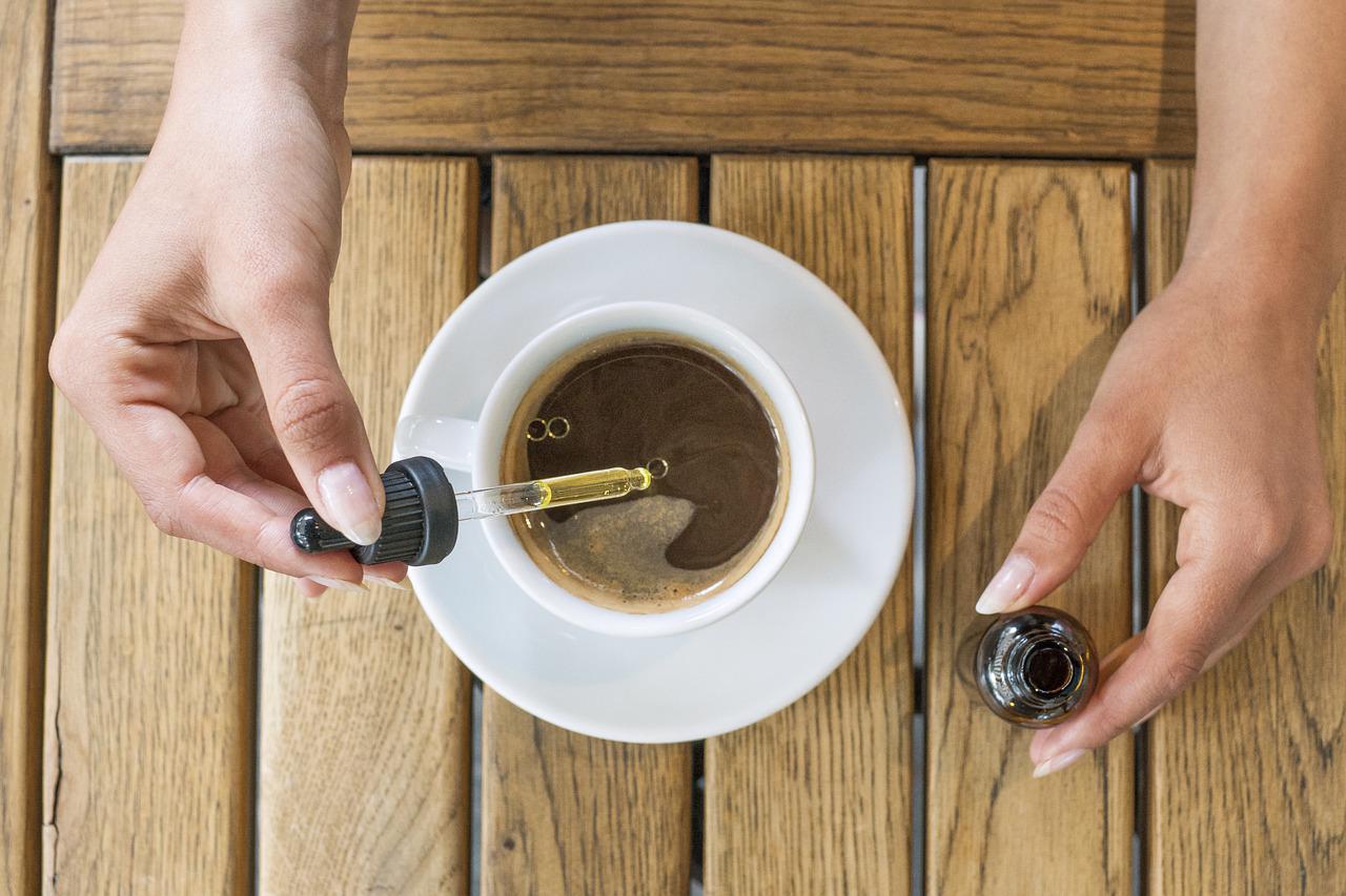 Person dispensing cbd oil into a cup of coffee