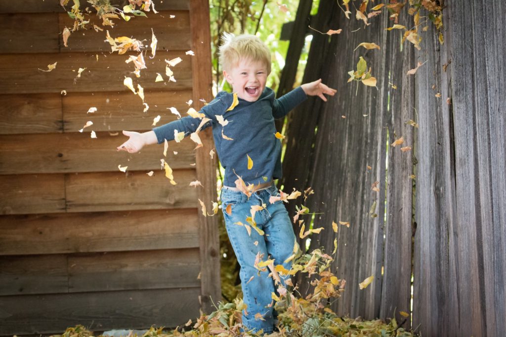 boy near fence with falling leaves