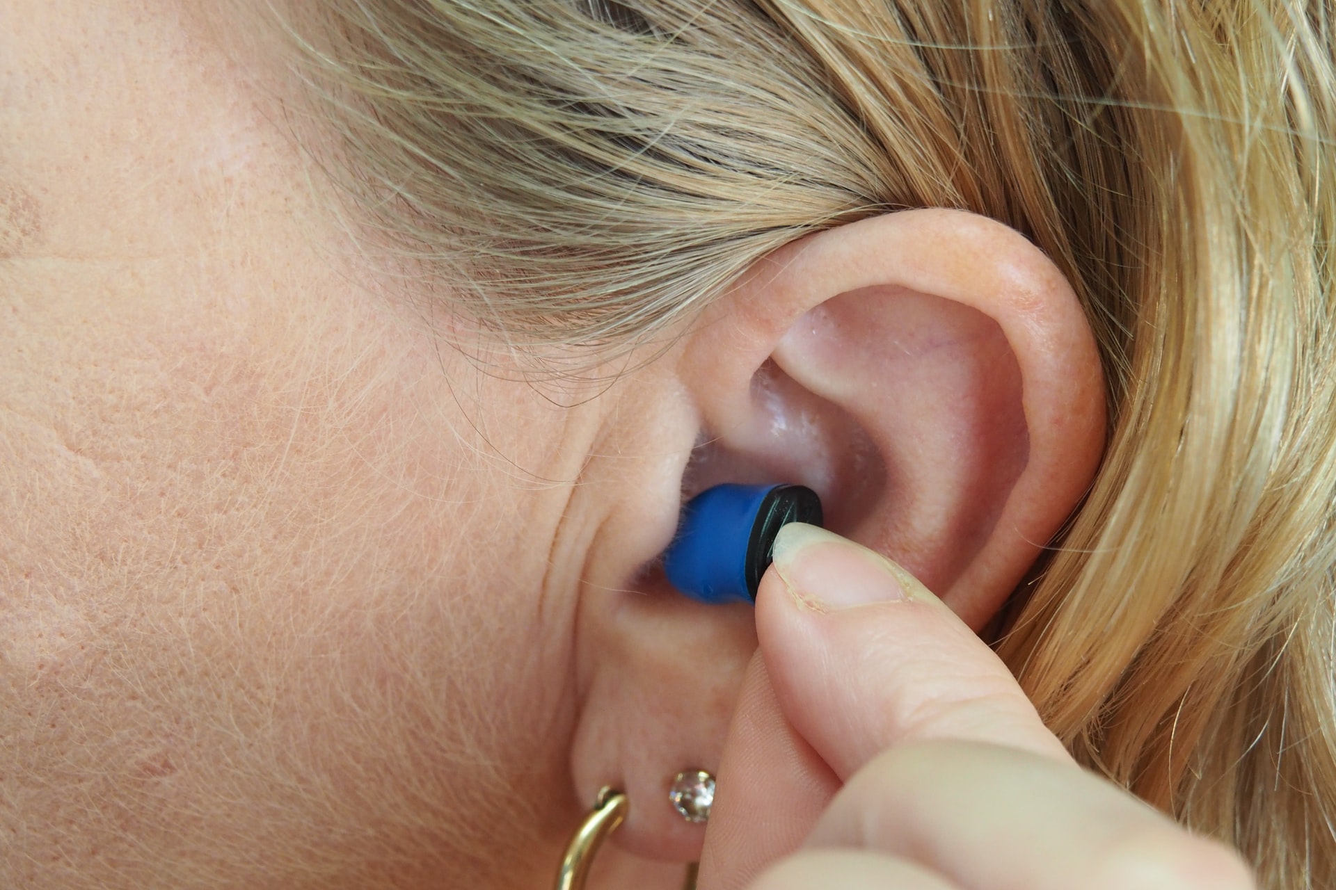 woman putting earplugs in her ears